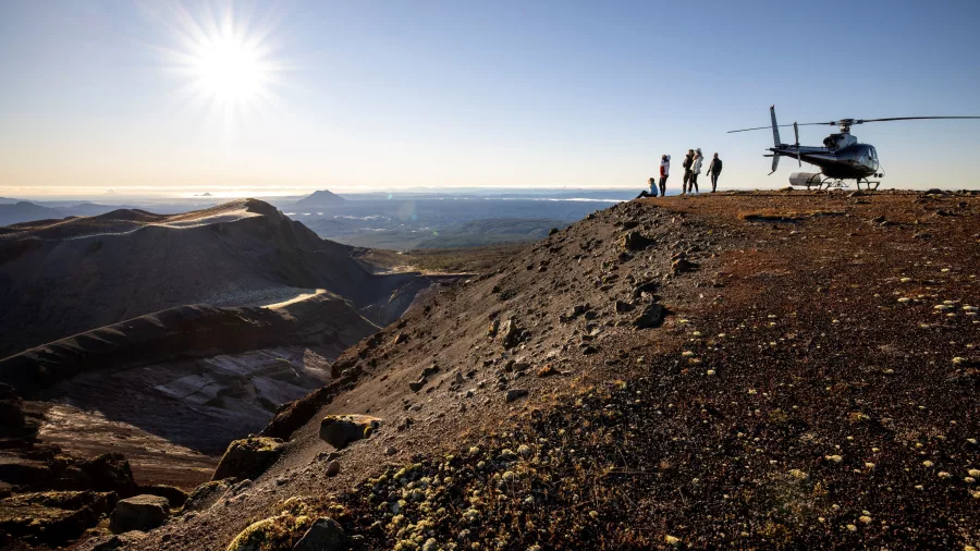 Helicopter landing on Mt Tarawera with sun low on the horizon