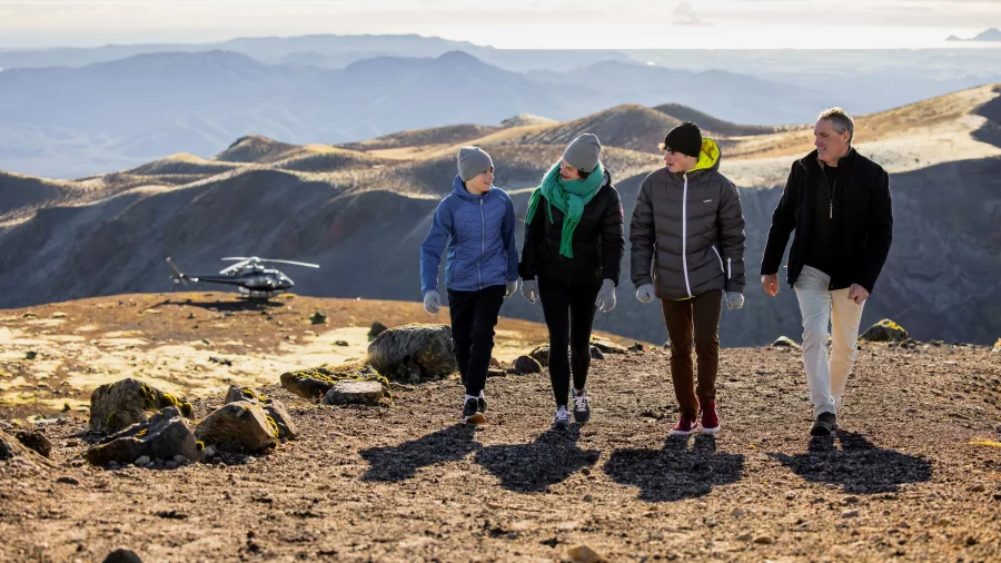 Family walking on Mt Tarawera with helicopter parked in the distance
