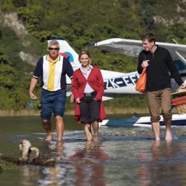 Group walking from a Volcanic Air floatplane after landing on a lakeside picnic spot