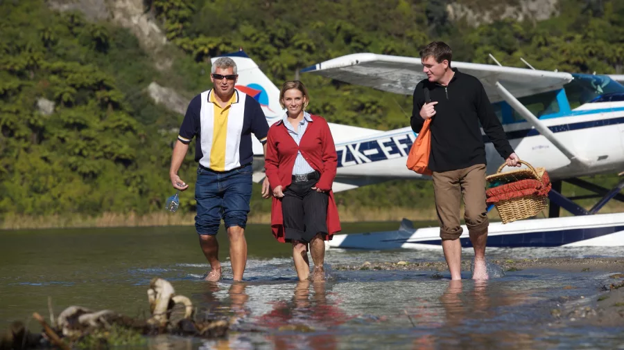 Group walking from a Volcanic Air floatplane after landing on a lakeside picnic spot