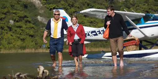 Group walking from a Volcanic Air floatplane after landing on a lakeside picnic spot