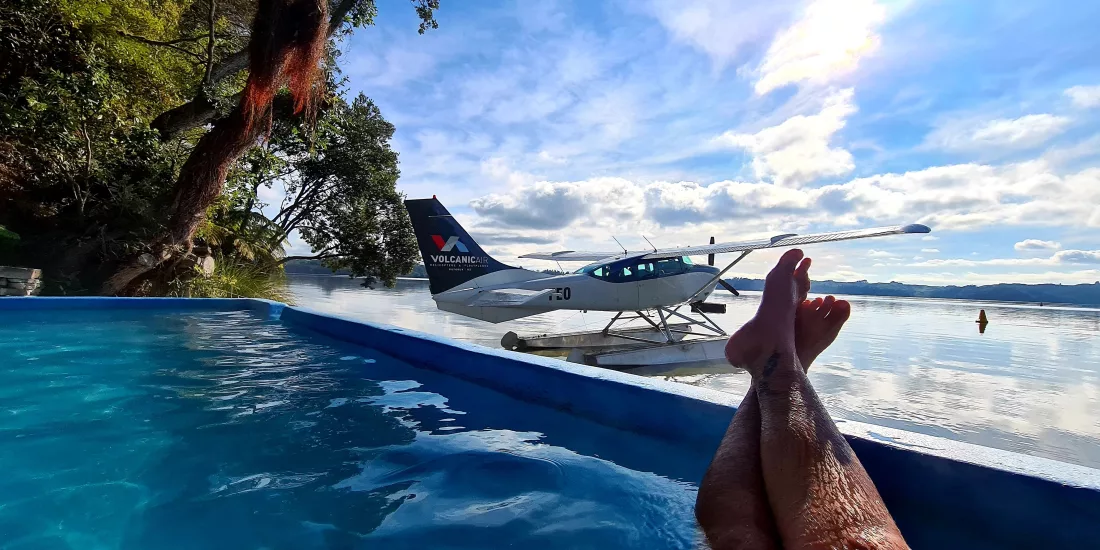 View of a floatplane on Lake Rotoiti from a hot pool, with legs in foreground