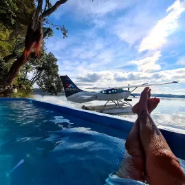 View of a floatplane on Lake Rotoiti from a hot pool, with legs in foreground