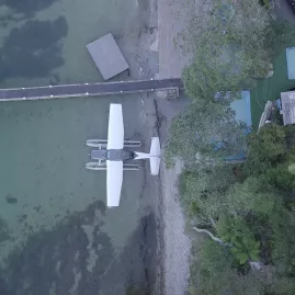 Top-down aerial view of Volcanic Air floatplane docked at Rotoiti Hot Pools jetty