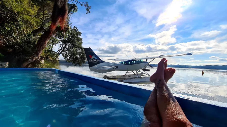View of a floatplane on Lake Rotoiti from a hot pool, with legs in foreground