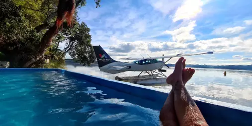 View of a floatplane on Lake Rotoiti from a hot pool, with legs in foreground