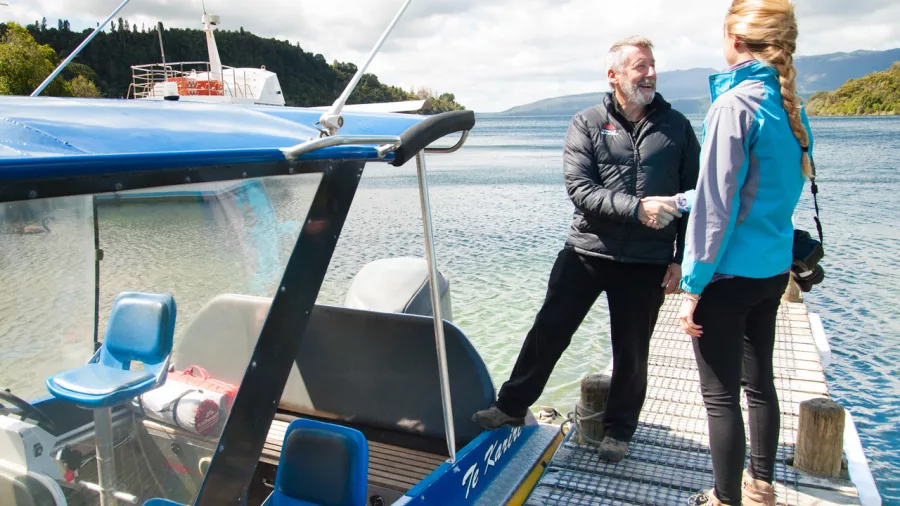 Guide greeting a guest beside the water taxi at Tapahoro Bay on Lake Tarawera