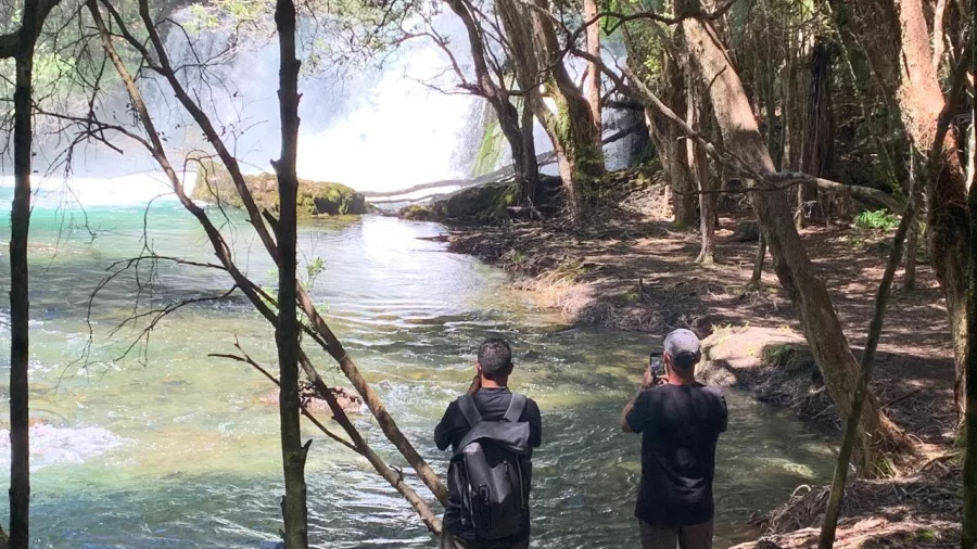 Two people taking photos at the base of Tarawera Falls