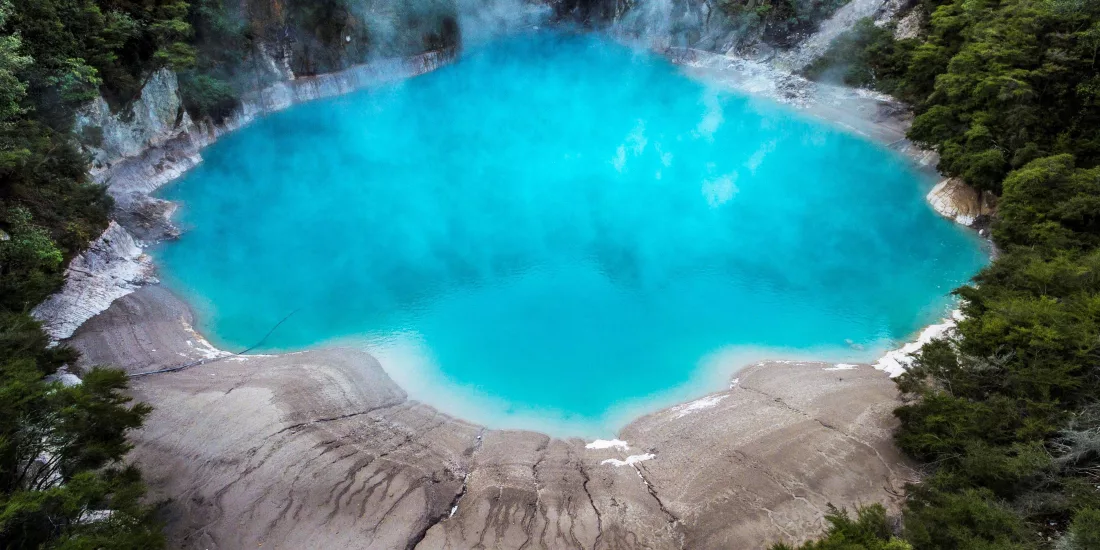 Bright blue Inferno Crater Lake emitting geothermal steam