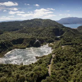 Wide aerial view of Frying Pan Lake steaming inside Waimangu Volcanic Valley