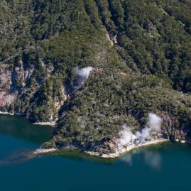 Geothermal steam vents rising from bush-clad cliffs at Lake Rotomahana