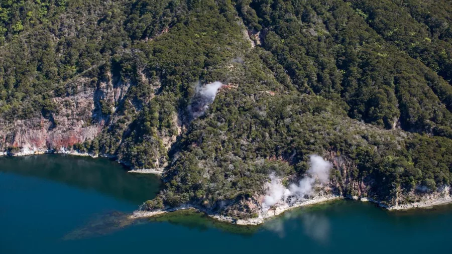 Geothermal steam vents rising from bush-clad cliffs at Lake Rotomahana