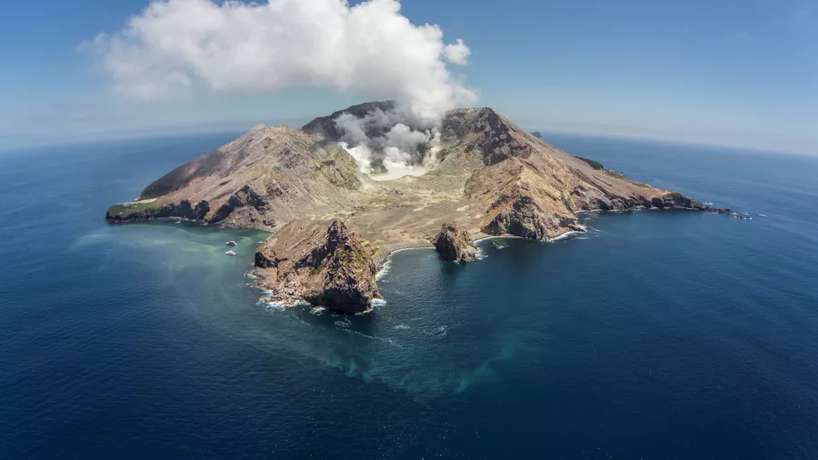 Aerial photo of White Island showing the steaming crater and surrounding coastline