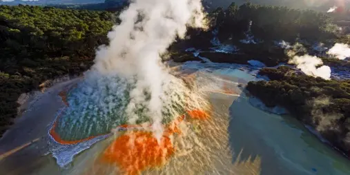 Champagne Pool at Wai-O-Tapu with vibrant orange edges, steaming water, and geothermal terraces