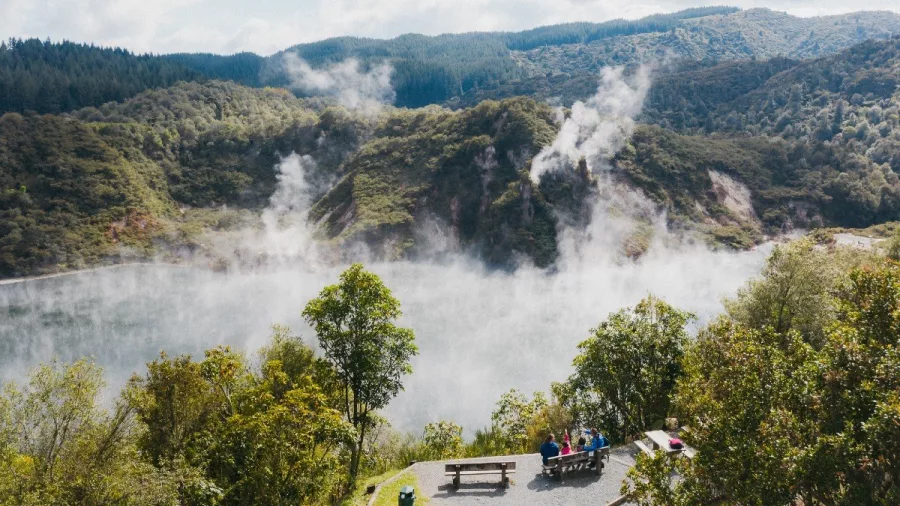 Visitors at a lookout above Frying Pan Lake with steam rising in Waimangu Volcanic Valley