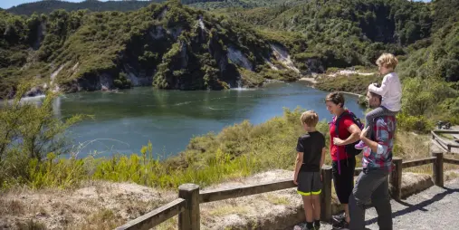 Family enjoying a scenic view over Frying Pan Lake in Waimangu Volcanic Valley, Rotorua