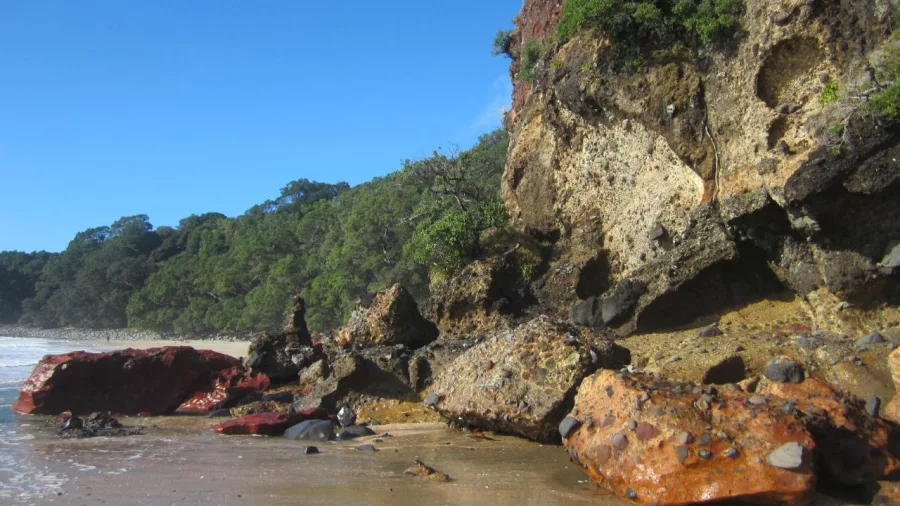 Colourful rock formations on the edge of New Chums Beach in the Coromandel