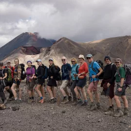 Group of hikers smiling with Mount Ngauruhoe and volcanic terrain in the background