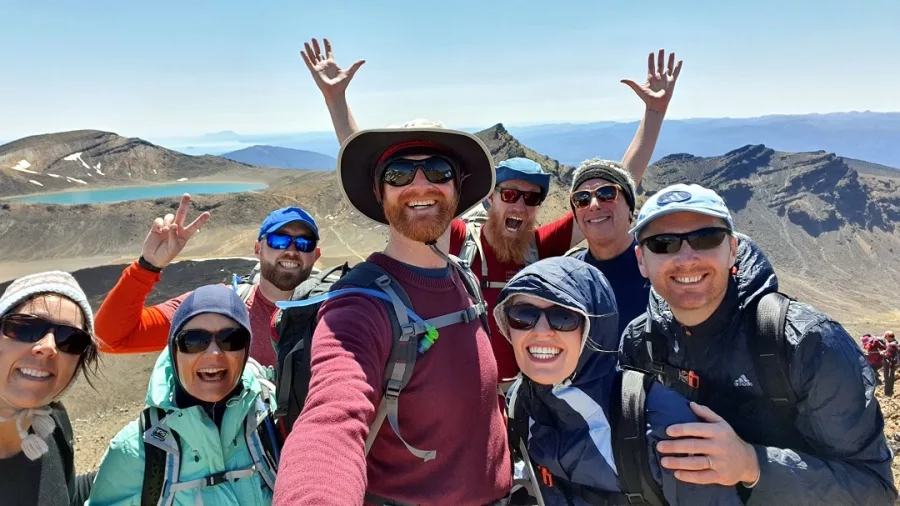 Happy hiking group taking a selfie on the Tongariro Alpine Crossing with stunning volcanic views behind