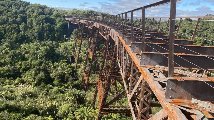 Historic iron viaduct surrounded by lush native bush on the Old Coach Road trail