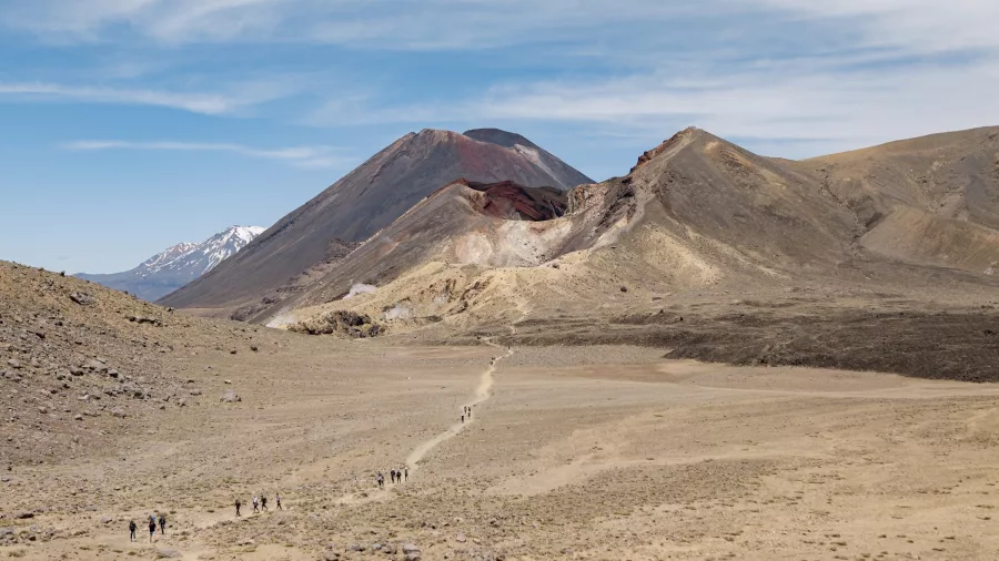 Wide-angle view of hikers crossing the volcanic plateau below Mount Ngauruhoe in Tongariro National Park