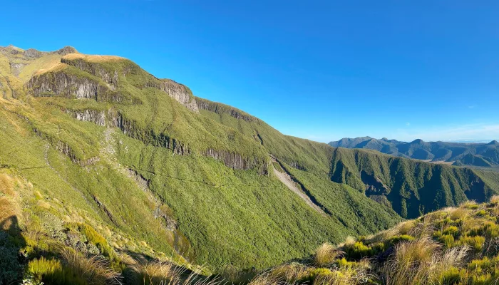 Wide-angle view over the Pouakai Range with sunlit ridges and expansive valleys