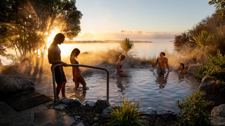 Visitors soaking in a thermal pool at Polynesian Spa, Rotorua, New Zealand, during sunrise