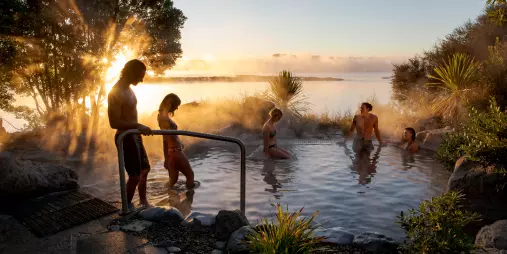 Visitors soaking in a thermal pool at Polynesian Spa, Rotorua, New Zealand, during sunrise