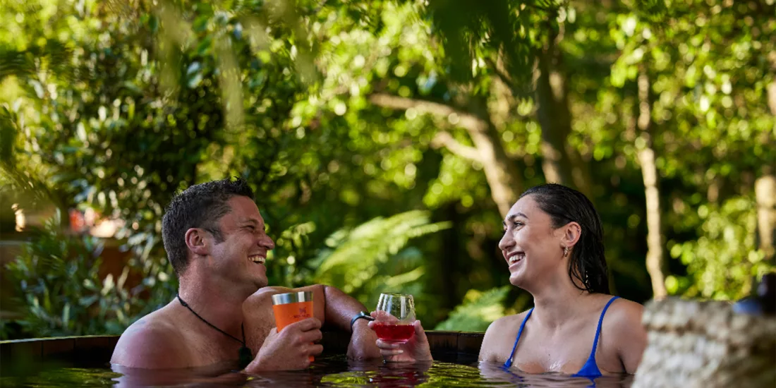 Couple enjoying drinks together in a cedar hot tub at Secret Spot Hot Tubs, Rotorua, New Zealand