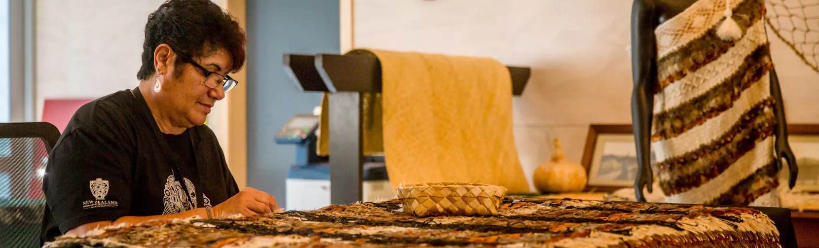 Māori weaver from Te Rito working on a fine feather cloak at Te Puia, Rotorua