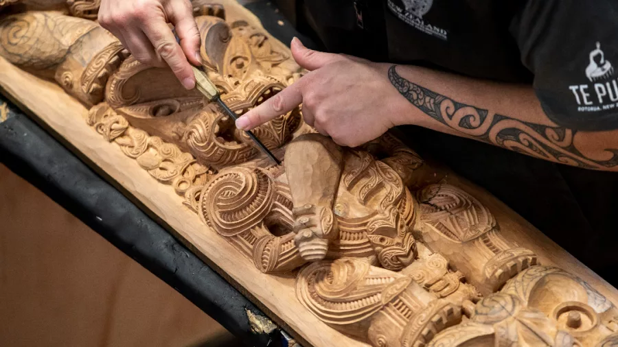 Māori carver working on a traditional pou at the New Zealand Māori Arts and Crafts Institute, Te Puia, Rotorua