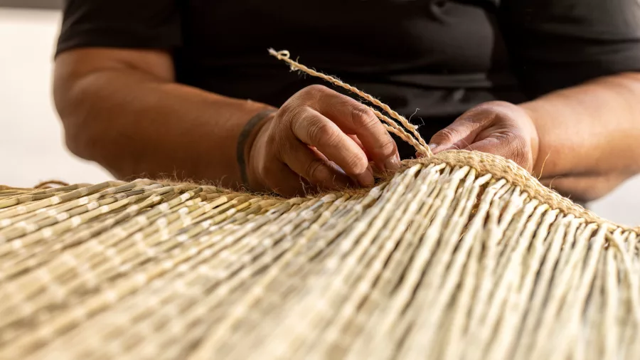 Hands weaving flax into traditional Māori craft at the New Zealand Māori Arts and Crafts Institute, Te Puia, Rotorua