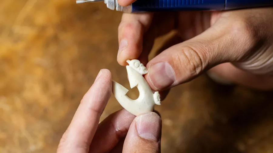 Artisan crafting a traditional Māori bone carving at Te Puia, Rotorua