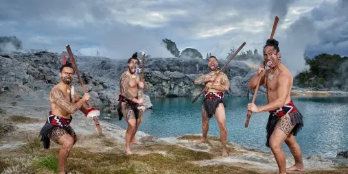 Māori performers in traditional dress holding taiaha at Te Puia geothermal valley