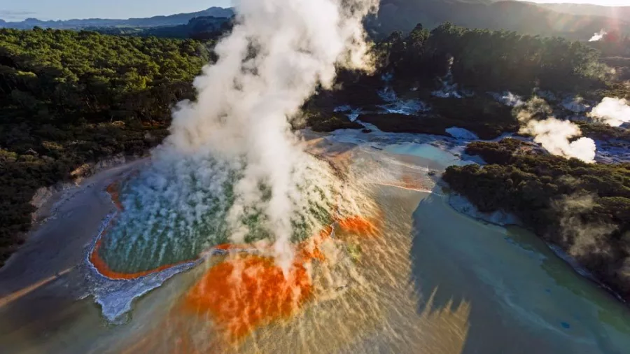 Champagne Pool at Wai-O-Tapu with vibrant orange edges, steaming water, and geothermal terraces
