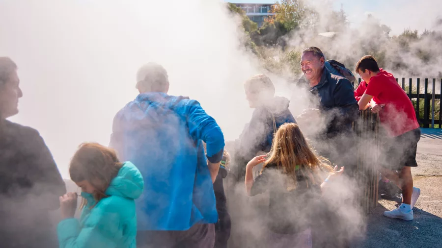 Visitors walking through geothermal steam at Whakarewarewa Māori Village in Rotorua