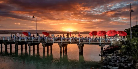 People gathered on Ohope Wharf at sunset in the Bay of Plenty, New Zealand
