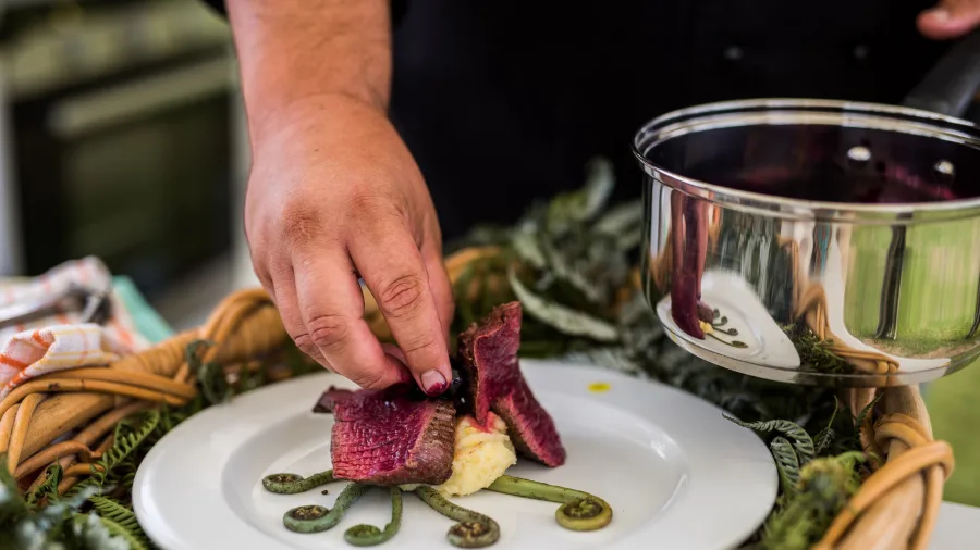 Chef plating a creative dish at the Local Wild Food Challenge in Ohope, Bay of Plenty, New Zealand