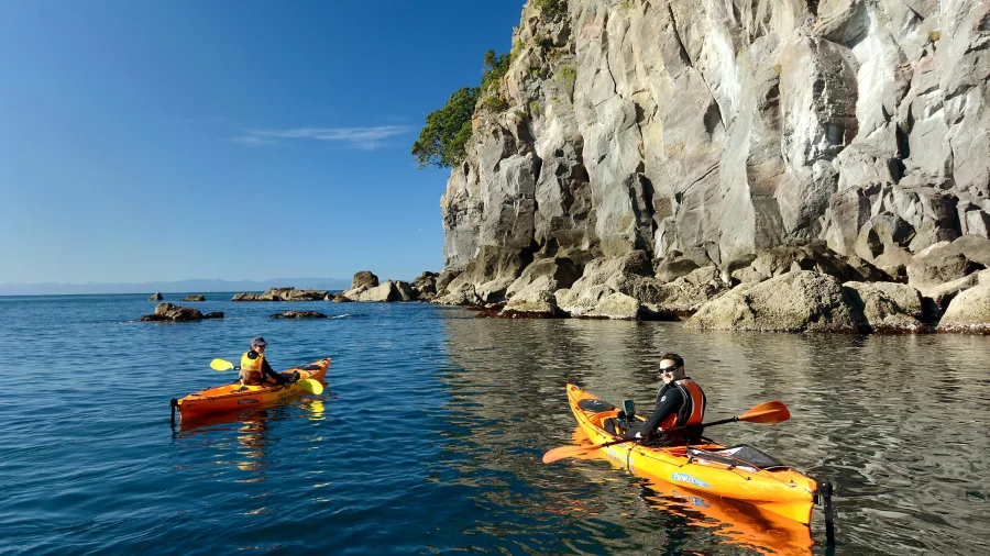 Two kayakers paddling around Whale Island Moutohora off the coast of Whakatane, Bay of Plenty, New Zealand