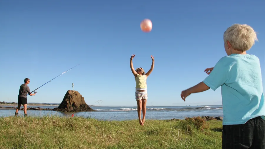 Family enjoying fishing and playing by the Whakatane River in the Bay of Plenty, New Zealand