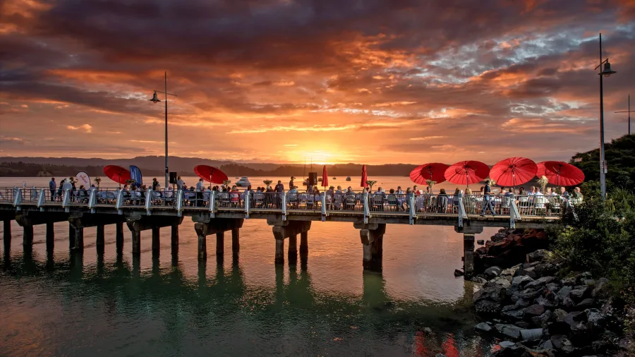 People gathered on Ohope Wharf at sunset in the Bay of Plenty, New Zealand