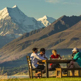 Group dining outdoors at Braemar Station with Mount Sefton rising in the background.