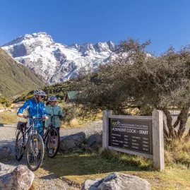 Two cyclists setting off from the official start sign of the Alps 2 Ocean Trail near Aoraki/Mt Cook.
