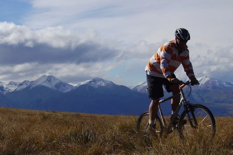 Mountain biker rides through golden tussock in high country terrain near Omarama.