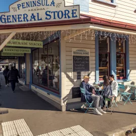 People enjoying coffee outside Peninsula General Store in Akaroa, New Zealand