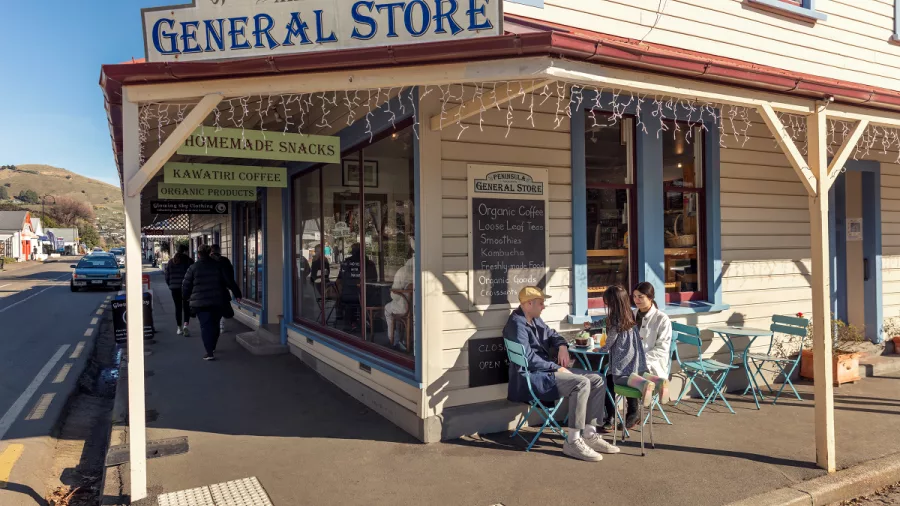 People enjoying coffee outside Peninsula General Store in Akaroa, New Zealand