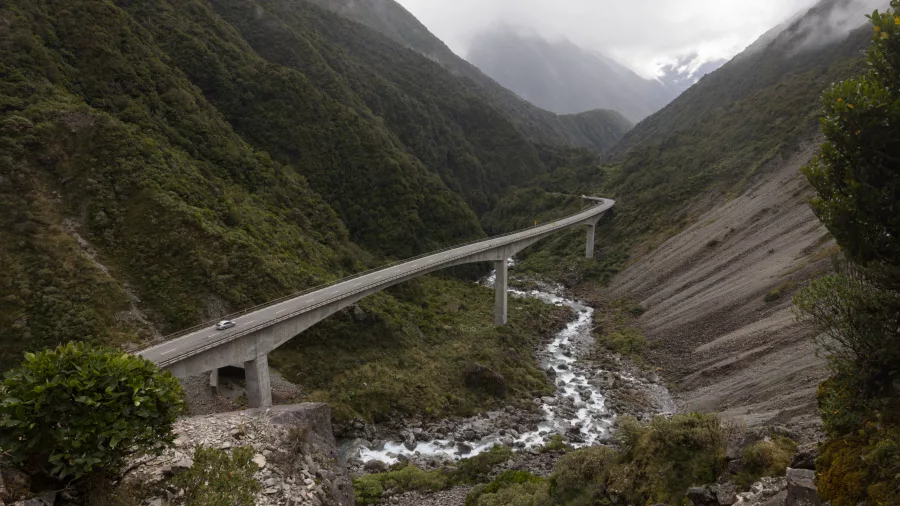 Vehicles travelling along the Otira Viaduct surrounded by rugged mountain terrain
