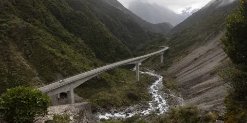 Vehicles travelling along the Otira Viaduct surrounded by rugged mountain terrain