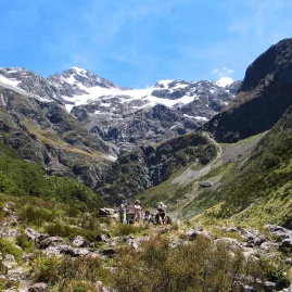 Hikers exploring the rocky trail in Upper Bealey Valley surrounded by snow-capped peaks