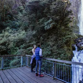 Couple enjoying the view from Devil’s Punchbowl lookout at Arthur’s Pass waterfall